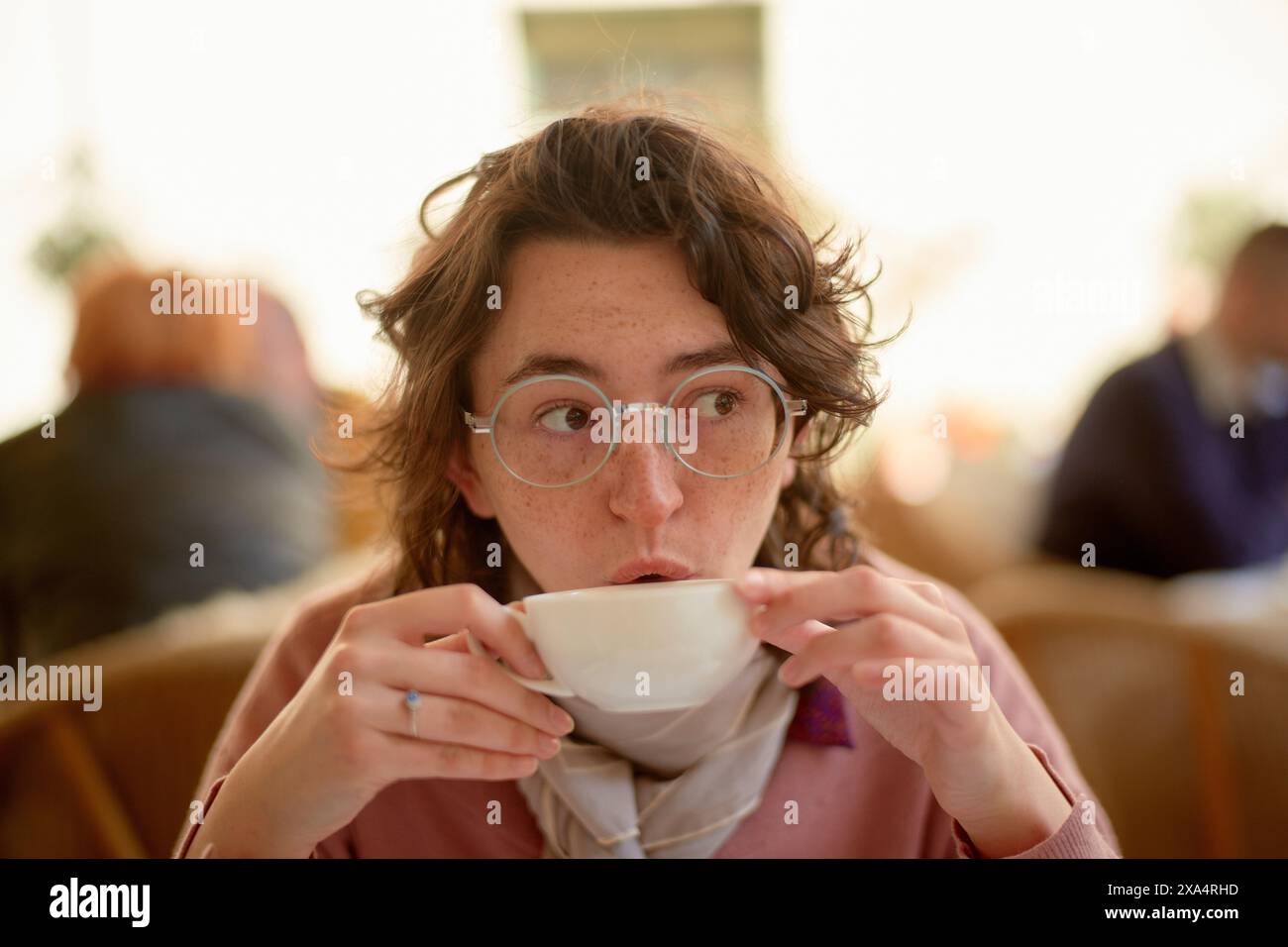 Donna che gusta una bevanda calda in un accogliente ambiente Cafè Foto Stock