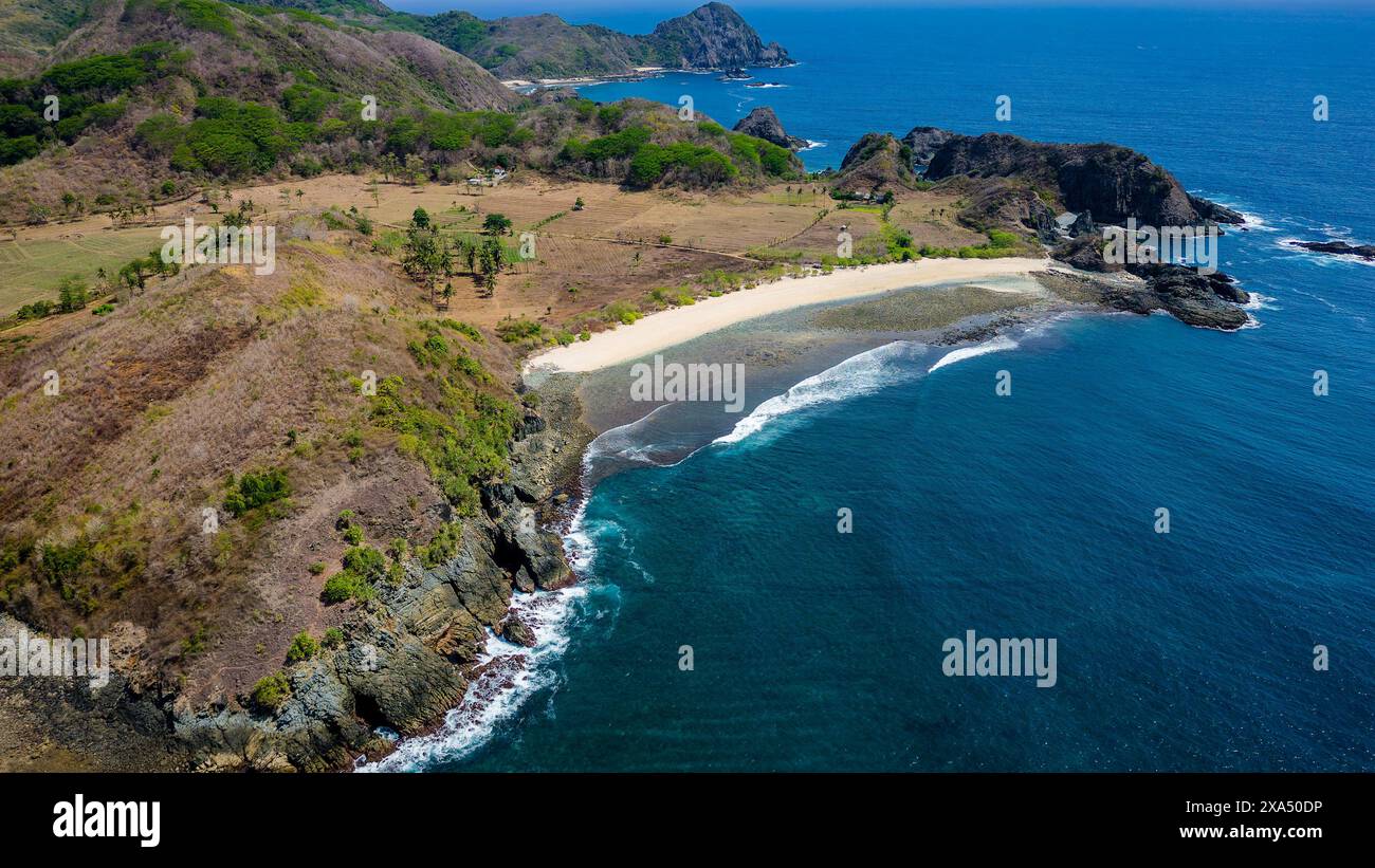 Vista aerea di una piccola spiaggia tropicale vuota circondata dall'oceano blu (Semeti Beach, Lombok) Foto Stock