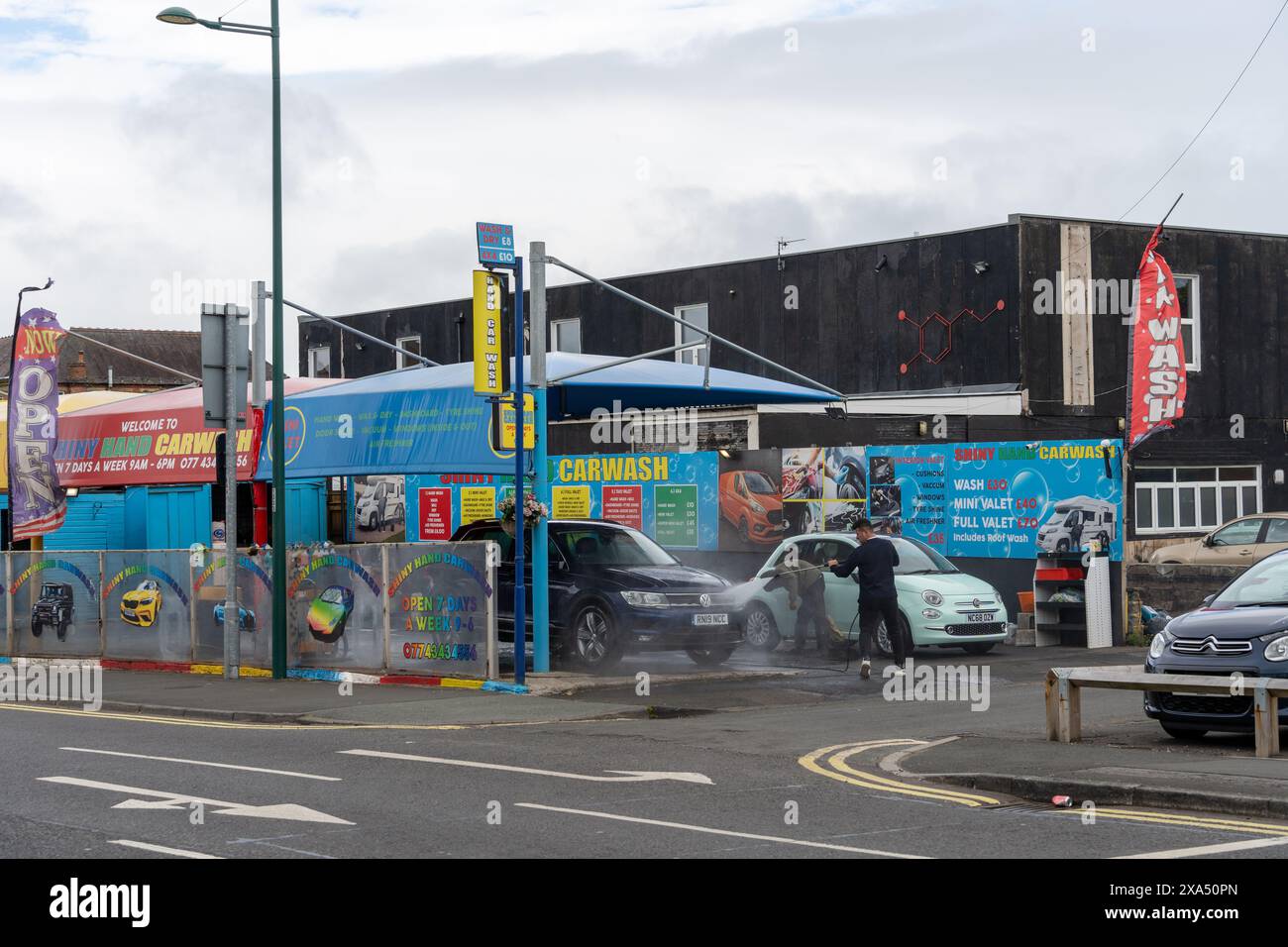 Consett, Contea di Durham, Regno Unito. Scena di strada nell'ex città siderurgica con gente che lavora sodo per pulire le auto all'autolavaggio. Foto Stock