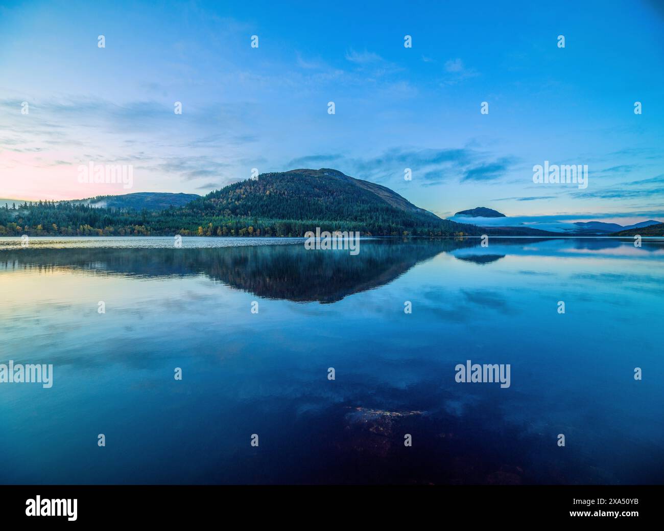 Tranquillo lago con riflessi a specchio sotto un cielo crepuscolo con nuvole sparse. Loch Lochy Foto Stock