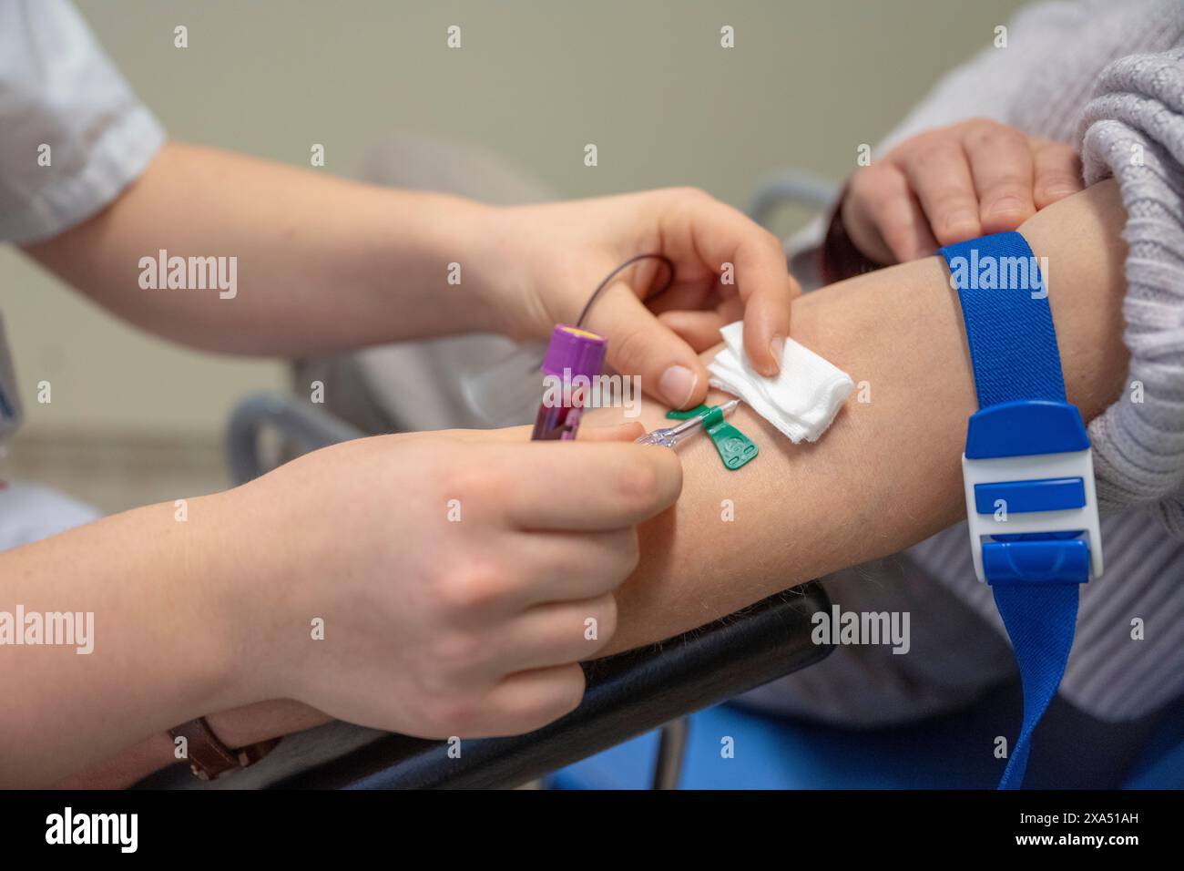 Un operatore sanitario preleva il sangue dal braccio di un paziente per un test medico in ambiente clinico. Foto Stock