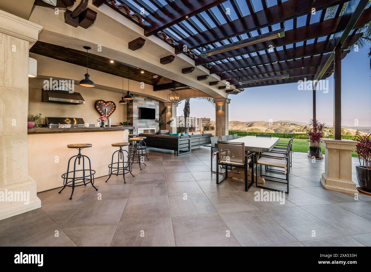Una cucina all'aperto con un ampio bar e due tavoli su un portico Foto Stock