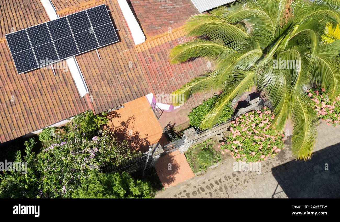 Tetto della casa con pannelli solari sullo sfondo soleggiato dei tropici Foto Stock
