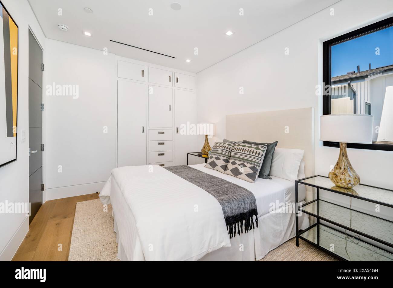 Una camera da letto con pareti bianche e pavimenti in legno Foto Stock