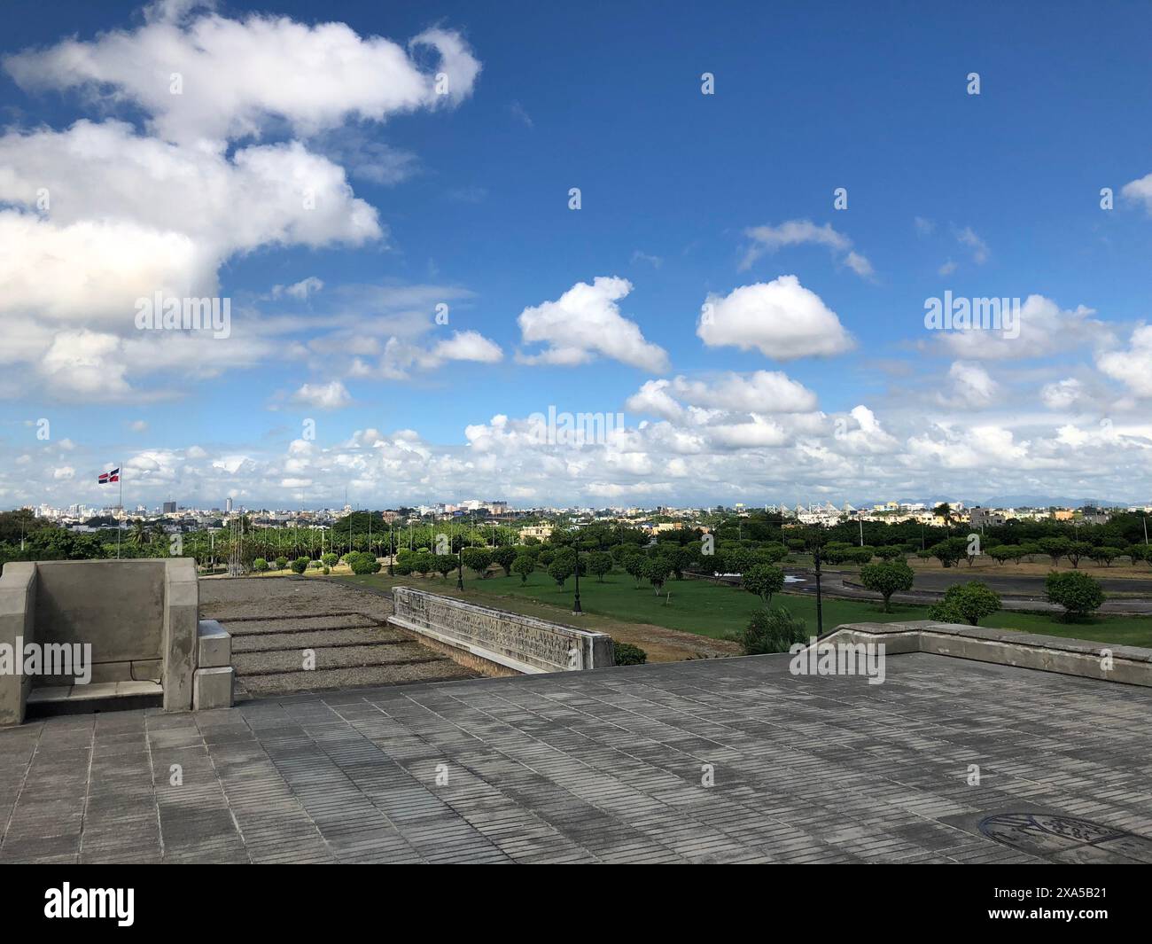 Un campo erboso sotto soffici nuvole con alcuni edifici nella Repubblica Dominicana Foto Stock