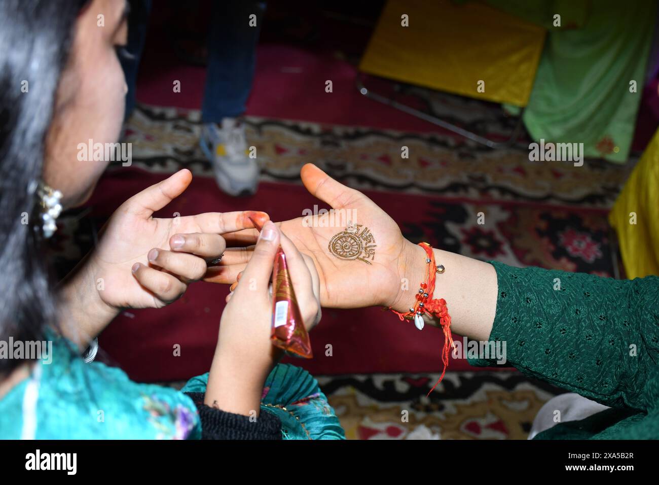 Due persone in piedi con le mani che toccano, tenendo insieme un oggetto in una cerimonia Mehndi Foto Stock