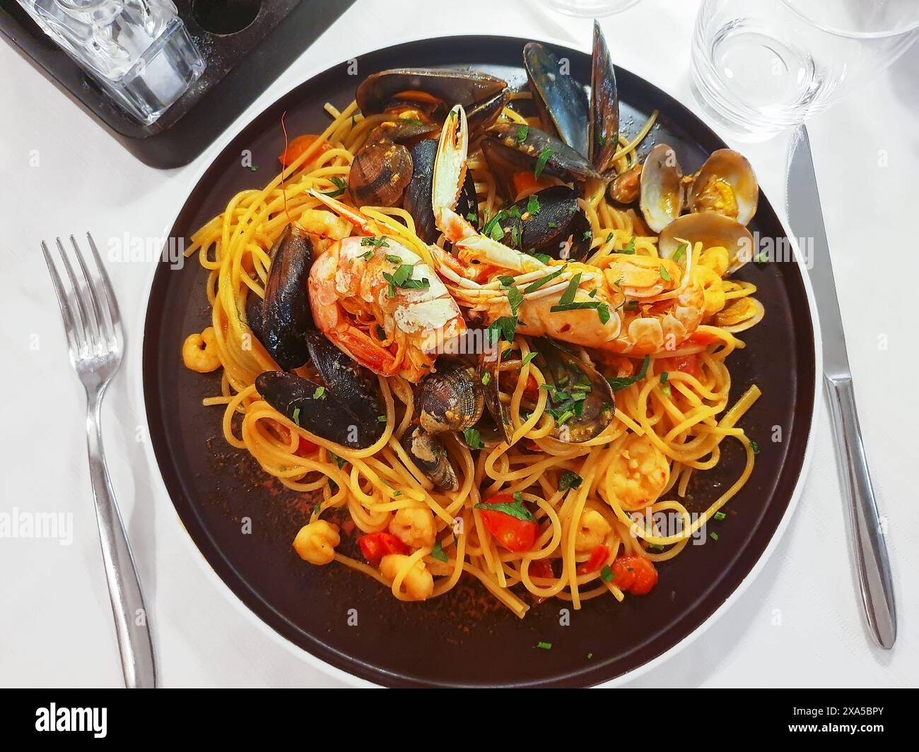 Classici spaghetti italiani di pasta a base di pesce con vongole, cozze, gamberi, cocktail di pesce sul tavolo scuro, primo piano. Spaghetti con salsa marinara. Foto Stock
