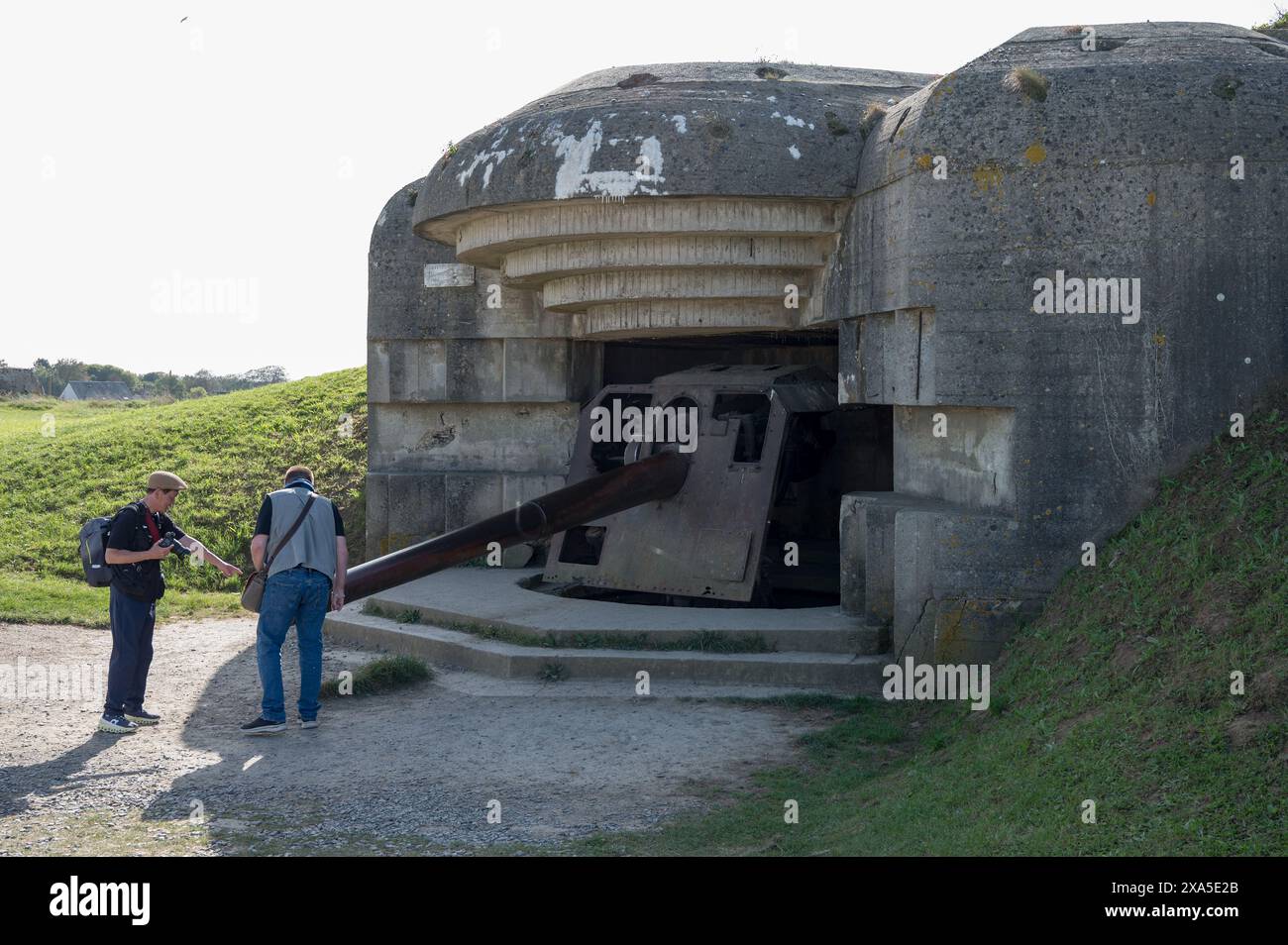 Dettaglio di alcuni turisti che osservano e toccano la batteria del cannone di artiglieria Longues-sur-Mer (batterie de Longues-sur-Mer) Foto Stock