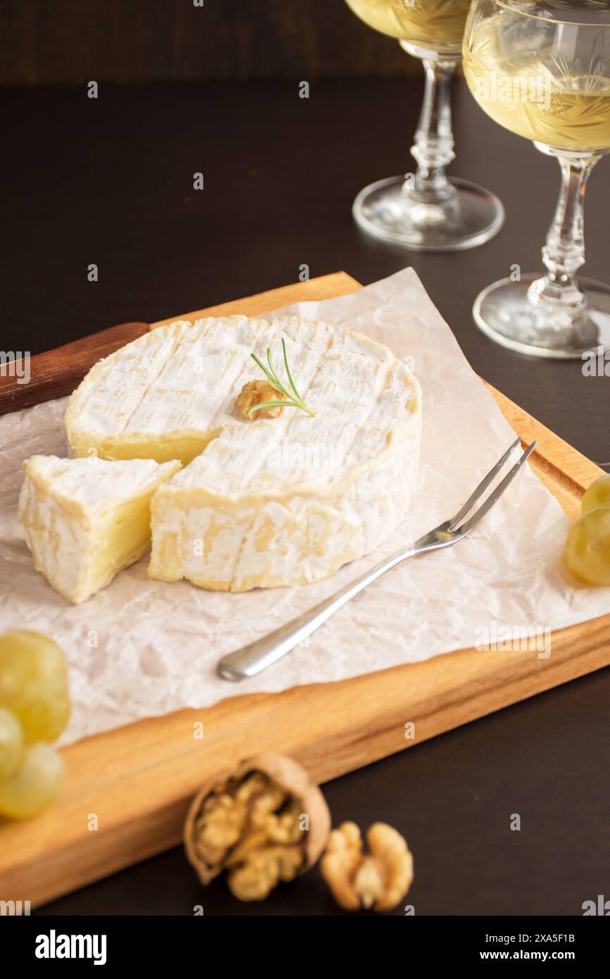 Un piatto con formaggio, noci, uva e bicchieri da vino Foto Stock