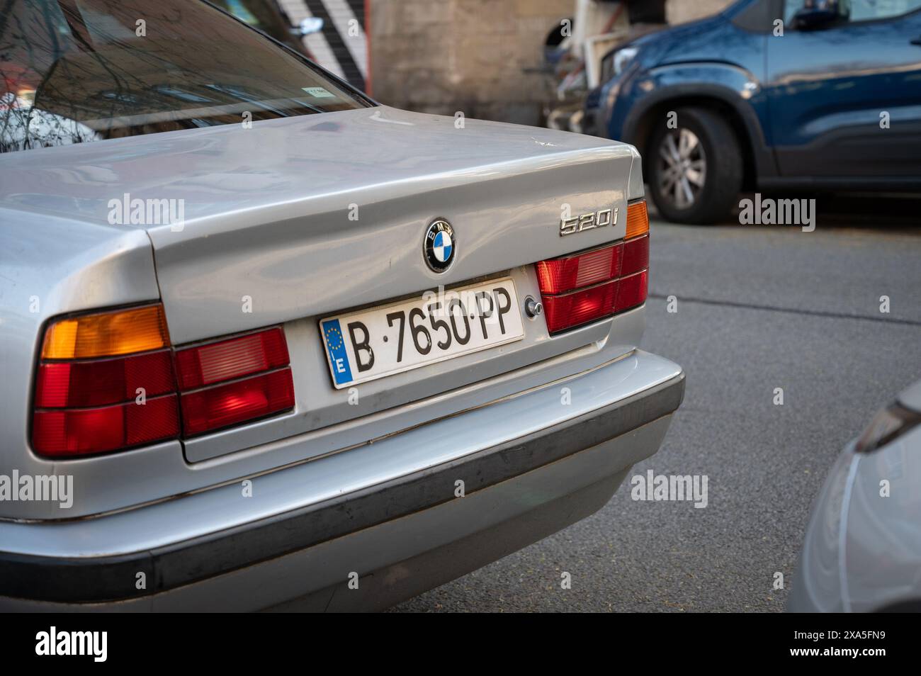 Una vecchia BMW 520i serie 5 generazione E34 color argento parcheggiata sulla strada della città di Barcellona Foto Stock