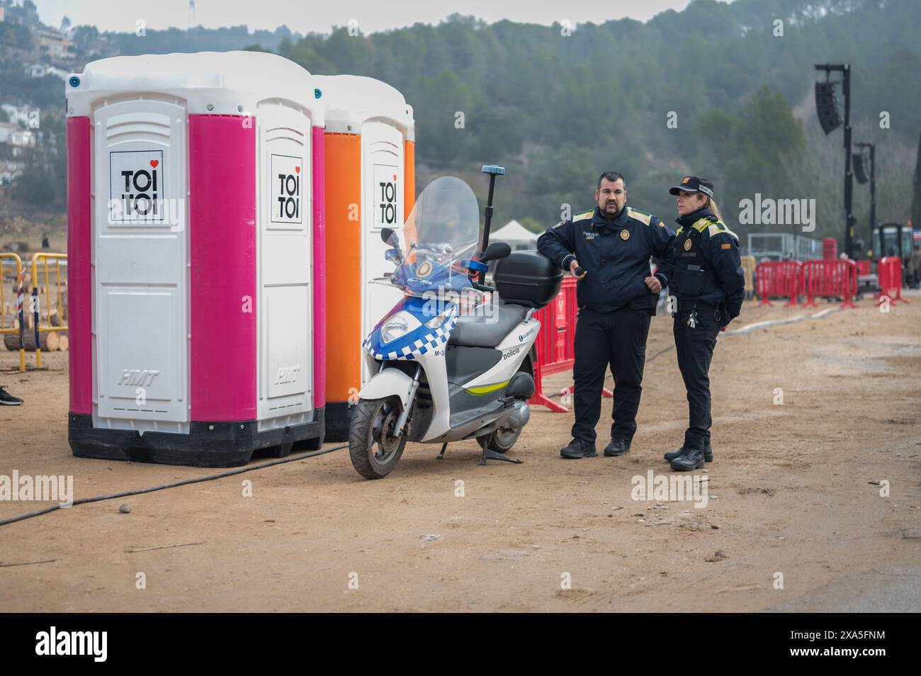 Gli agenti di polizia locali accanto allo scooter di pattuglia che pattuglia i festeggiamenti nella città di Torrelles de Llobregat Foto Stock