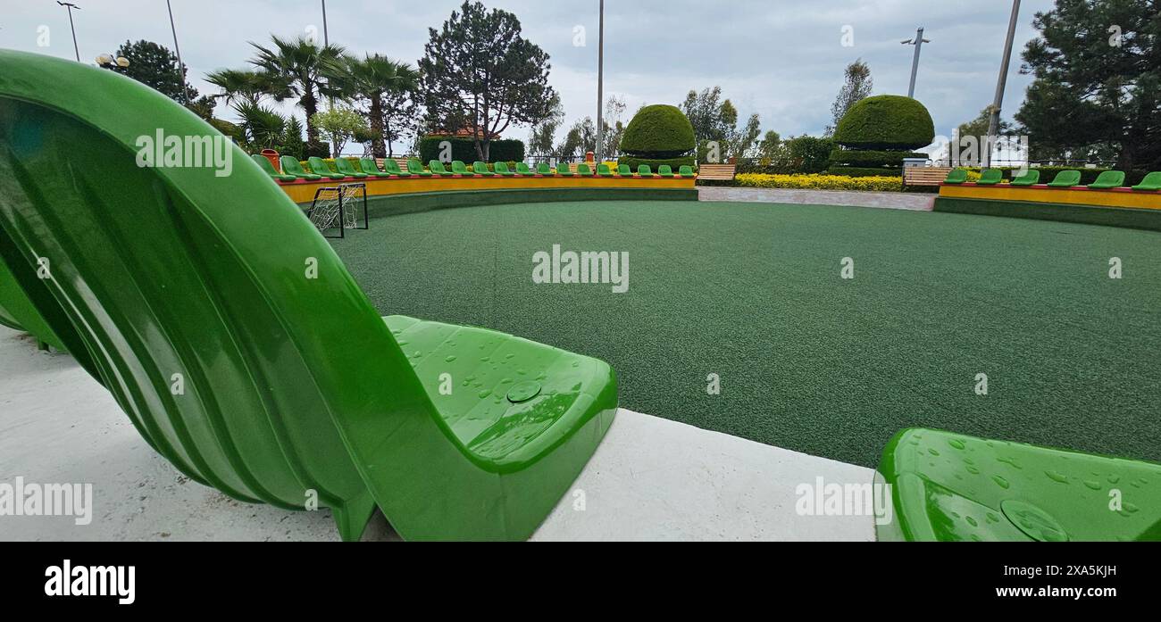 Una sedia verde siede su un tappeto erboso artificiale in città Foto Stock