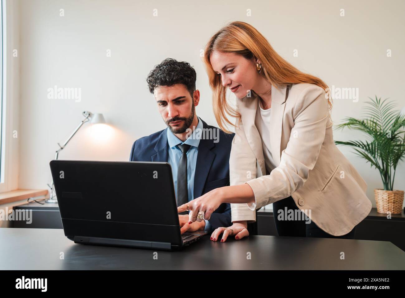 Una donna d'affari e un uomo d'affari che lavorano insieme con un notebook per un progetto di lavoro. Due veri colleghi che collaborano e pianificano utilizzando un computer. Lavoro di squadra dei dipendenti aziendali su un brainstorming. Foto di alta qualità Foto Stock
