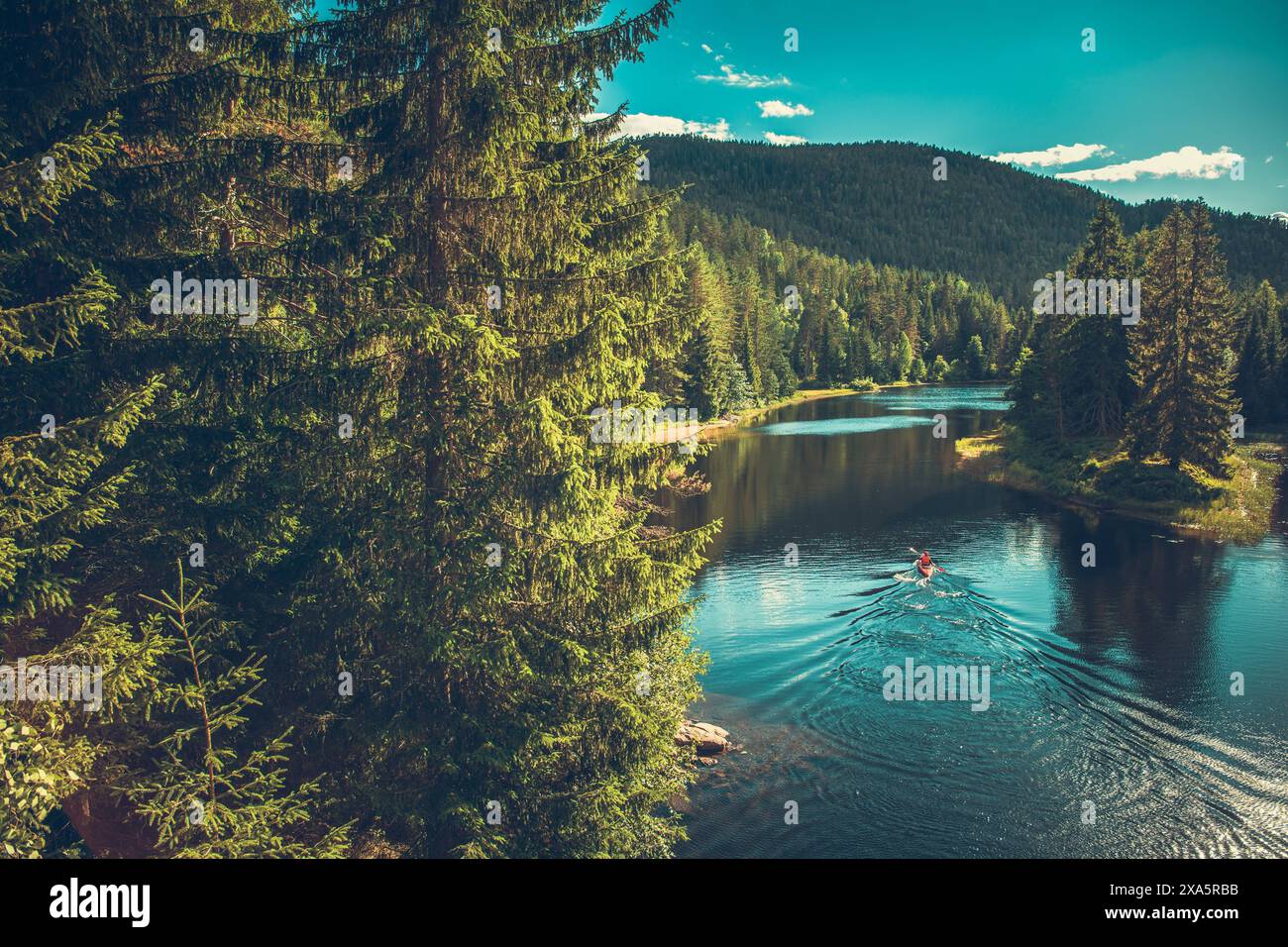 Un kayak sul fiume norvegese circondato da montagne e foreste Foto Stock