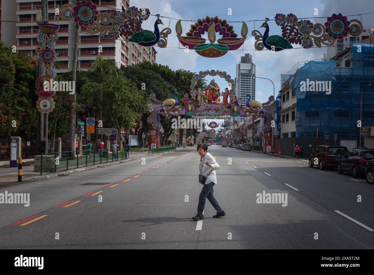 Una persona passeggia in una vivace strada cittadina in una giornata di sole Foto Stock