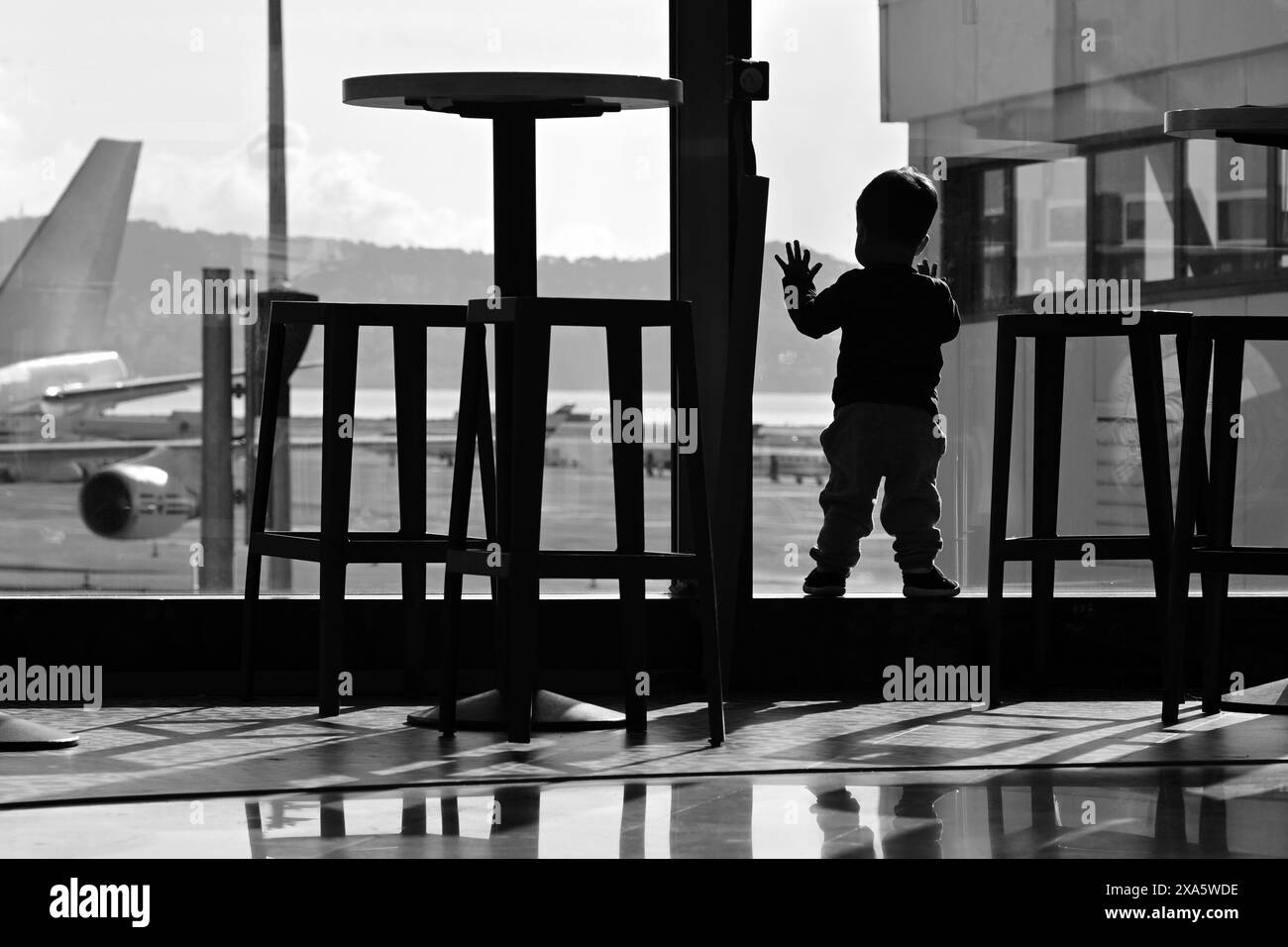 Aeroporto Nice Côte d'azur, Francia, 21 maggio 2024: Silhouette di bambini piccoli che guardano gli aerei al terminal dell'aeroporto in bianco e nero Foto Stock