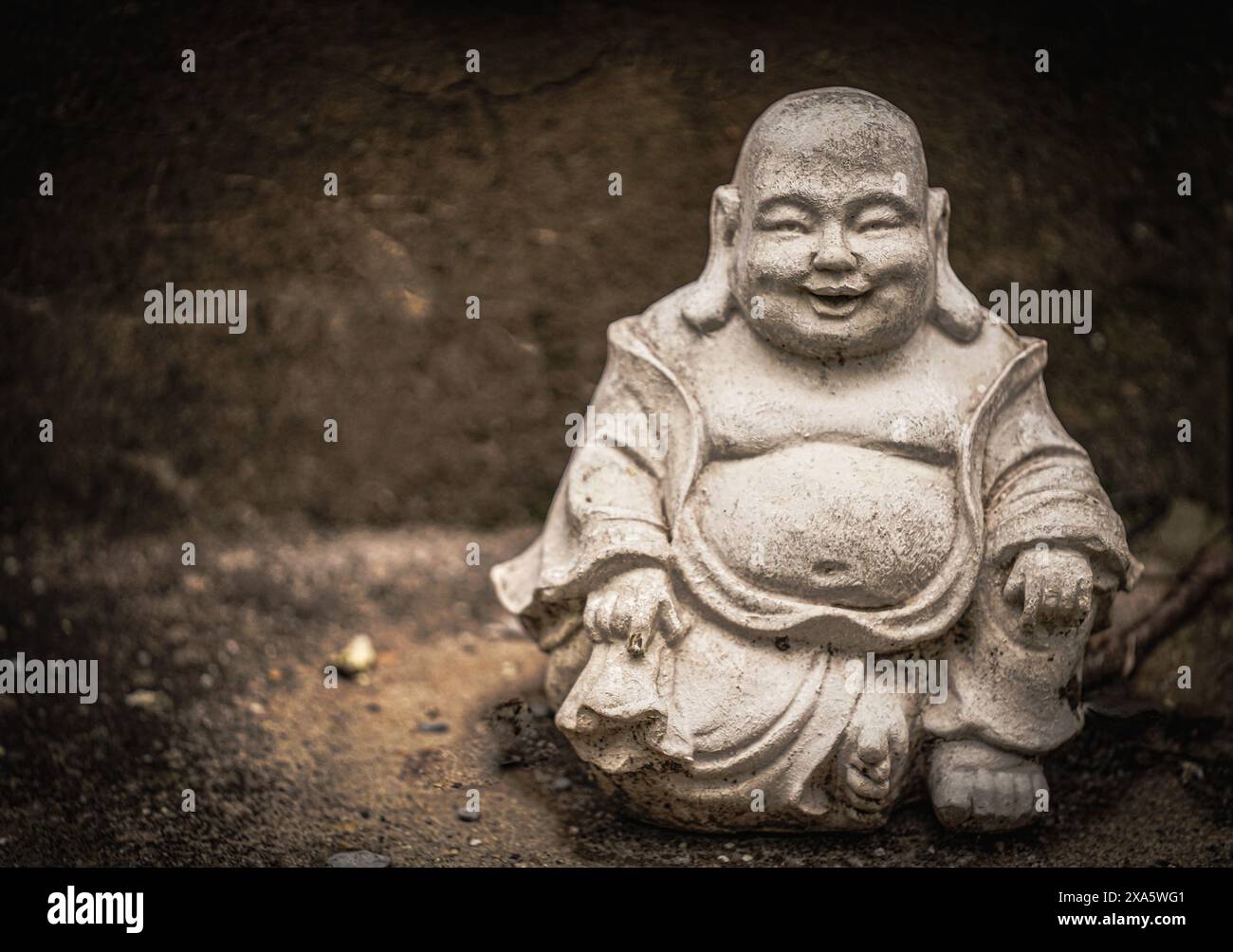 Una statua di Buddha seduta su cemento. Foto Stock