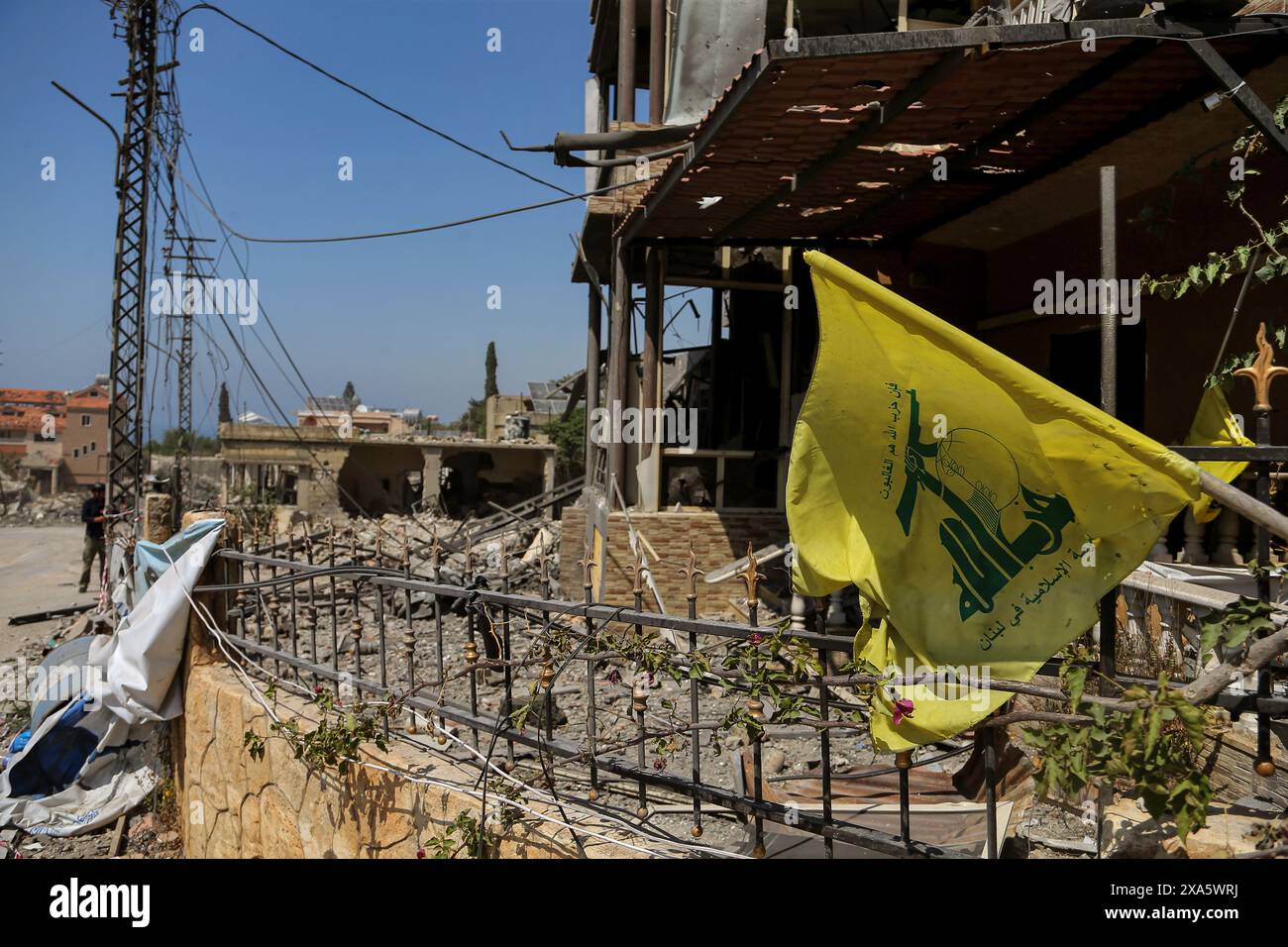 Naqura, Libano. 4 giugno 2024. Una bandiera di Hezbollah è appesa su macerie di case distrutte causate da incursioni aeree israeliane nel villaggio libanese meridionale di Naqura, situato al confine libanese-israeliano. Un drone israeliano ha fatto irruzione su una motocicletta uccidendo un militante di Hezbollah e ferendone pesantemente un altro. Crediti: Marwan Naamani/dpa/Alamy Live News Foto Stock