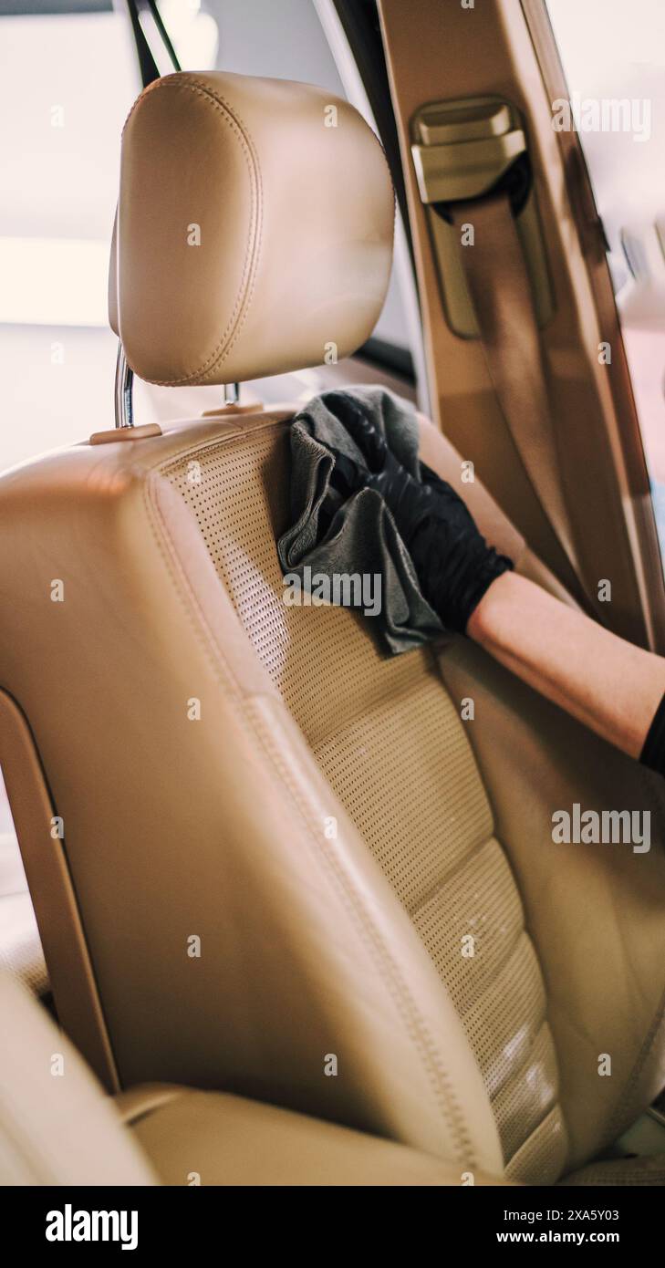 Una persona che indossa guanti per la pulizia degli interni di un'auto presso un'officina di riparazione Foto Stock