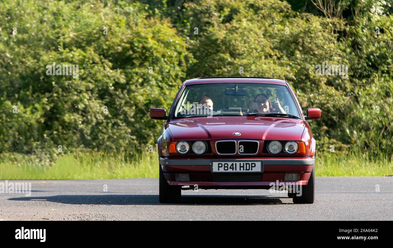 Stony Stratford, Regno Unito - 2 giugno 2024: 1996 BMW 518 rossa, auto d'epoca, su una strada di campagna britannica Foto Stock