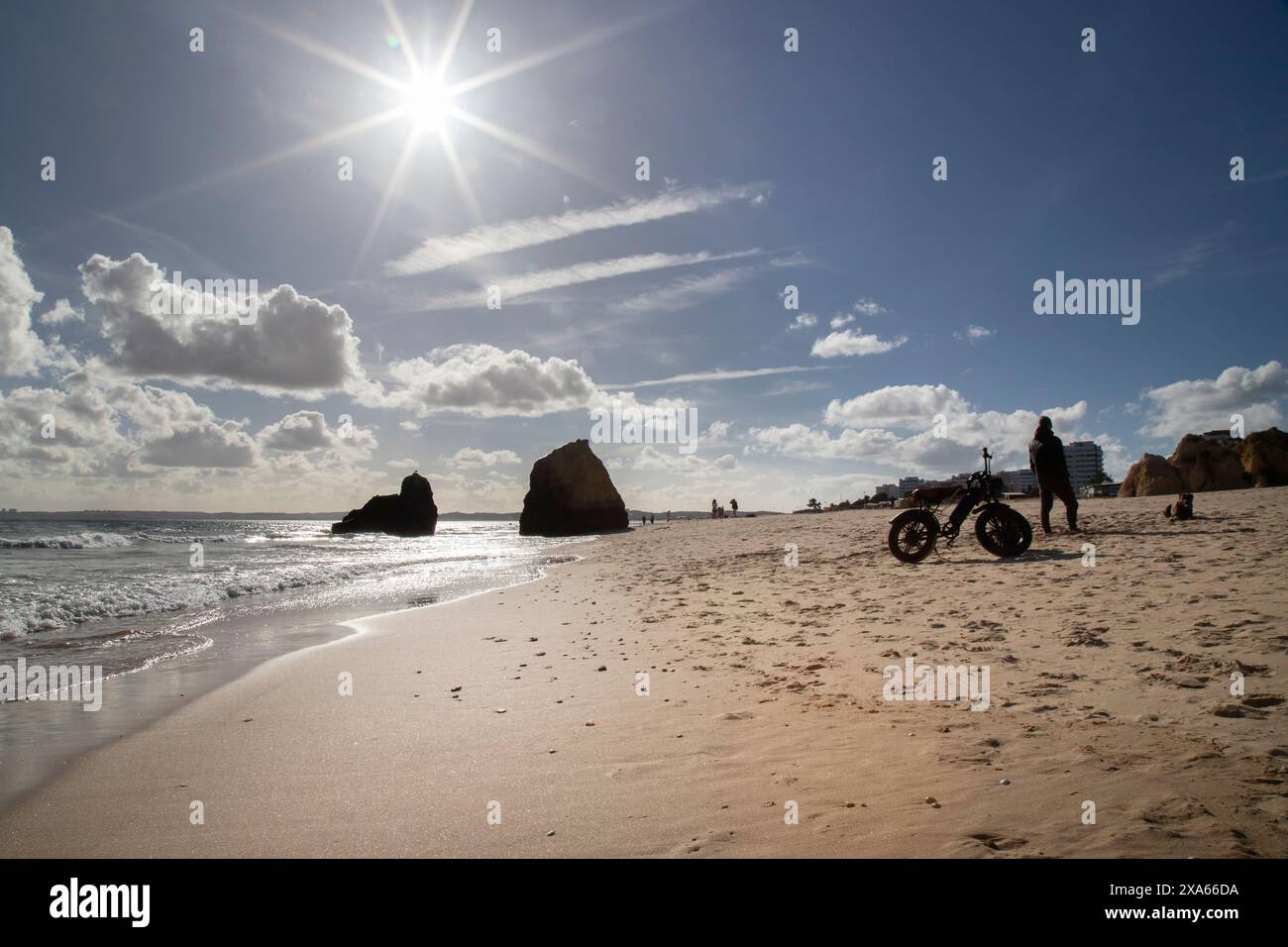 Un gruppo di individui che passeggiano lungo il litorale su una spiaggia sabbiosa Foto Stock