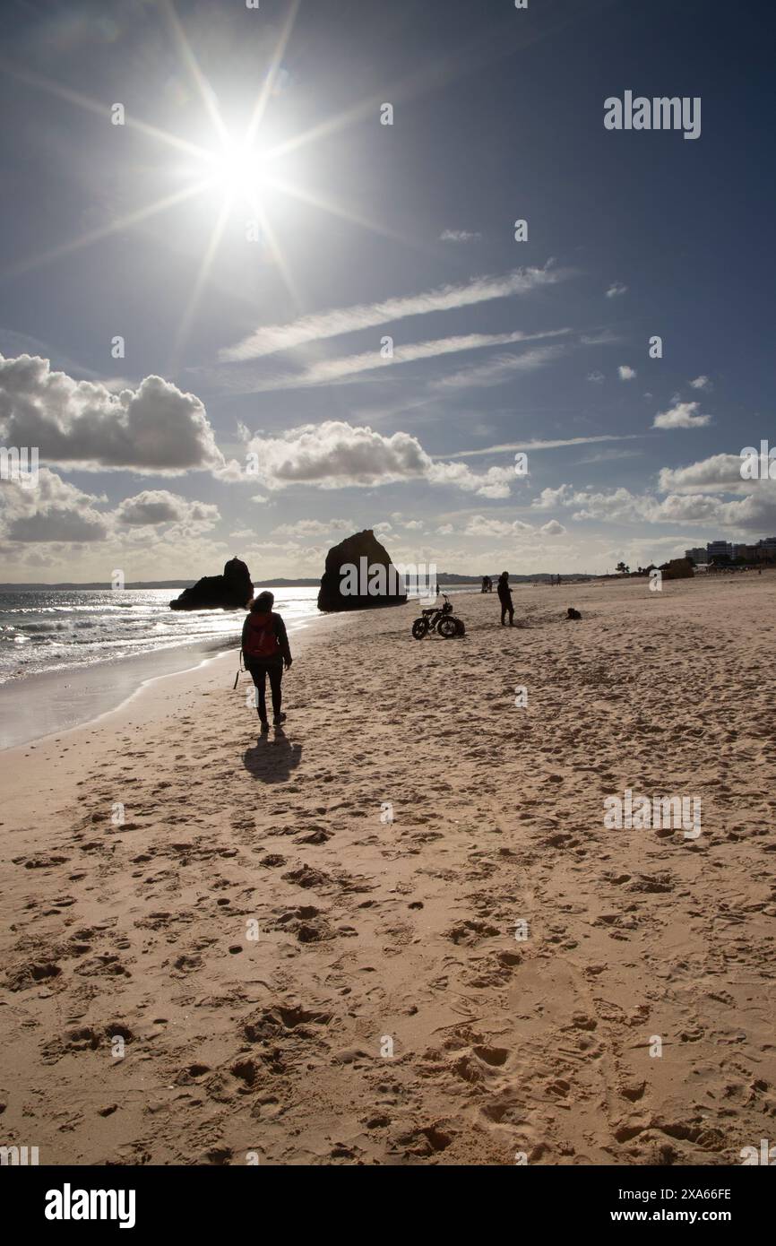 Un gruppo di individui che passeggiano lungo il litorale su una spiaggia sabbiosa Foto Stock
