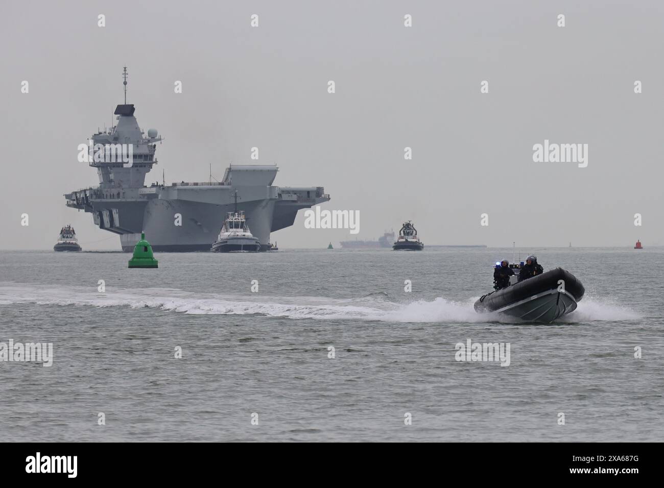 Ministero della difesa polizia di pattuglia mentre la portaerei HMS PRINCE OF WALES torna a casa dall'esercitazione Joint Warrior Foto Stock