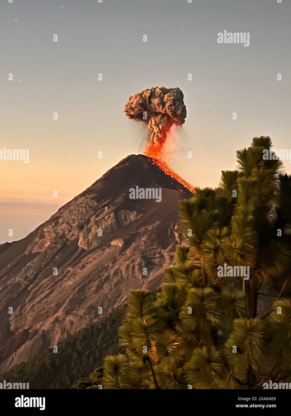Una montagna vulcanica che emette fumo arancione nel cielo Foto Stock