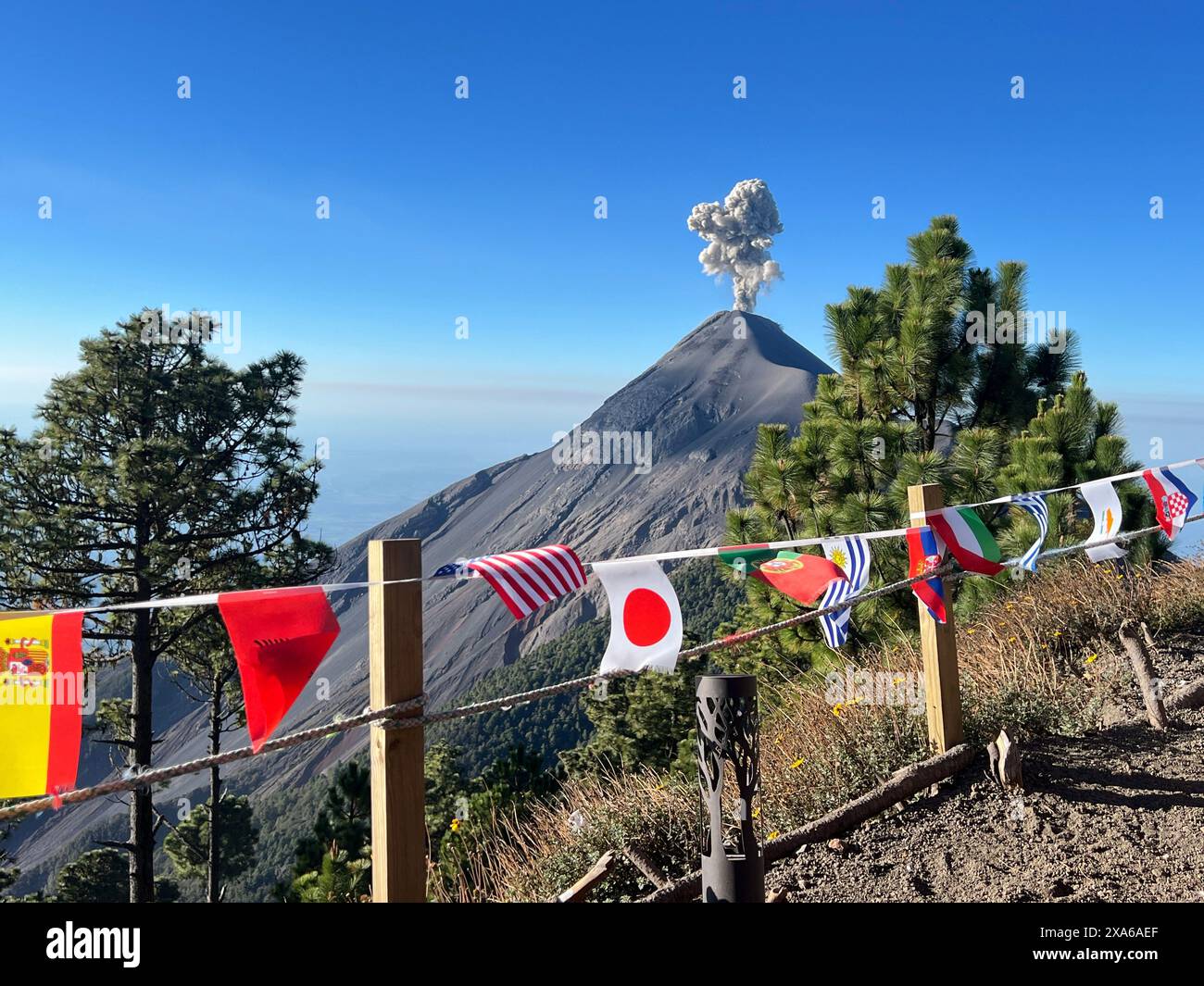 Bandiere colorate vicino alla montagna con nuvole di cenere sullo sfondo Foto Stock