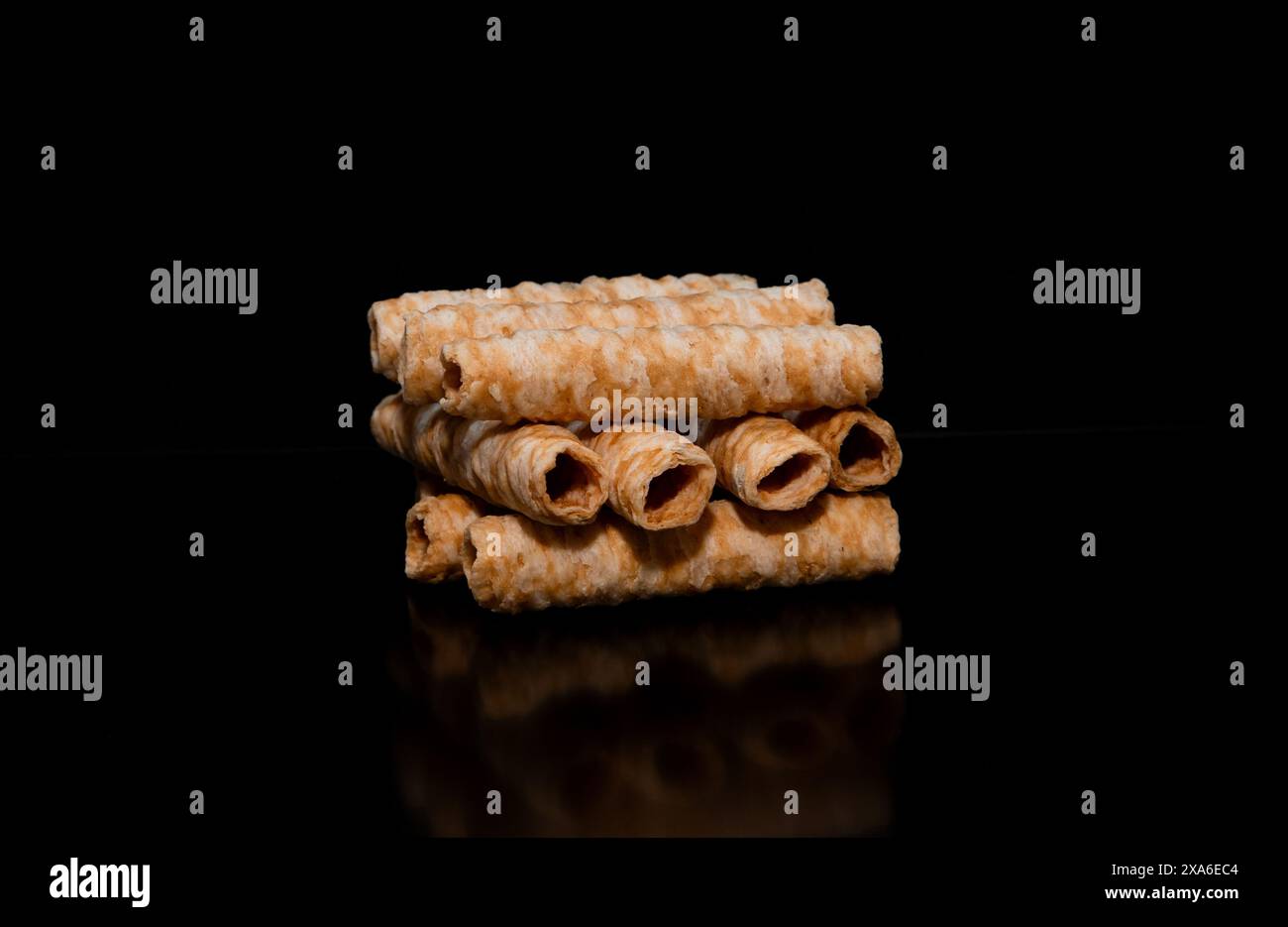 Molte cialde a forma di cilindro su sfondo nero, un mucchio di cialde croccanti al cocco Foto Stock
