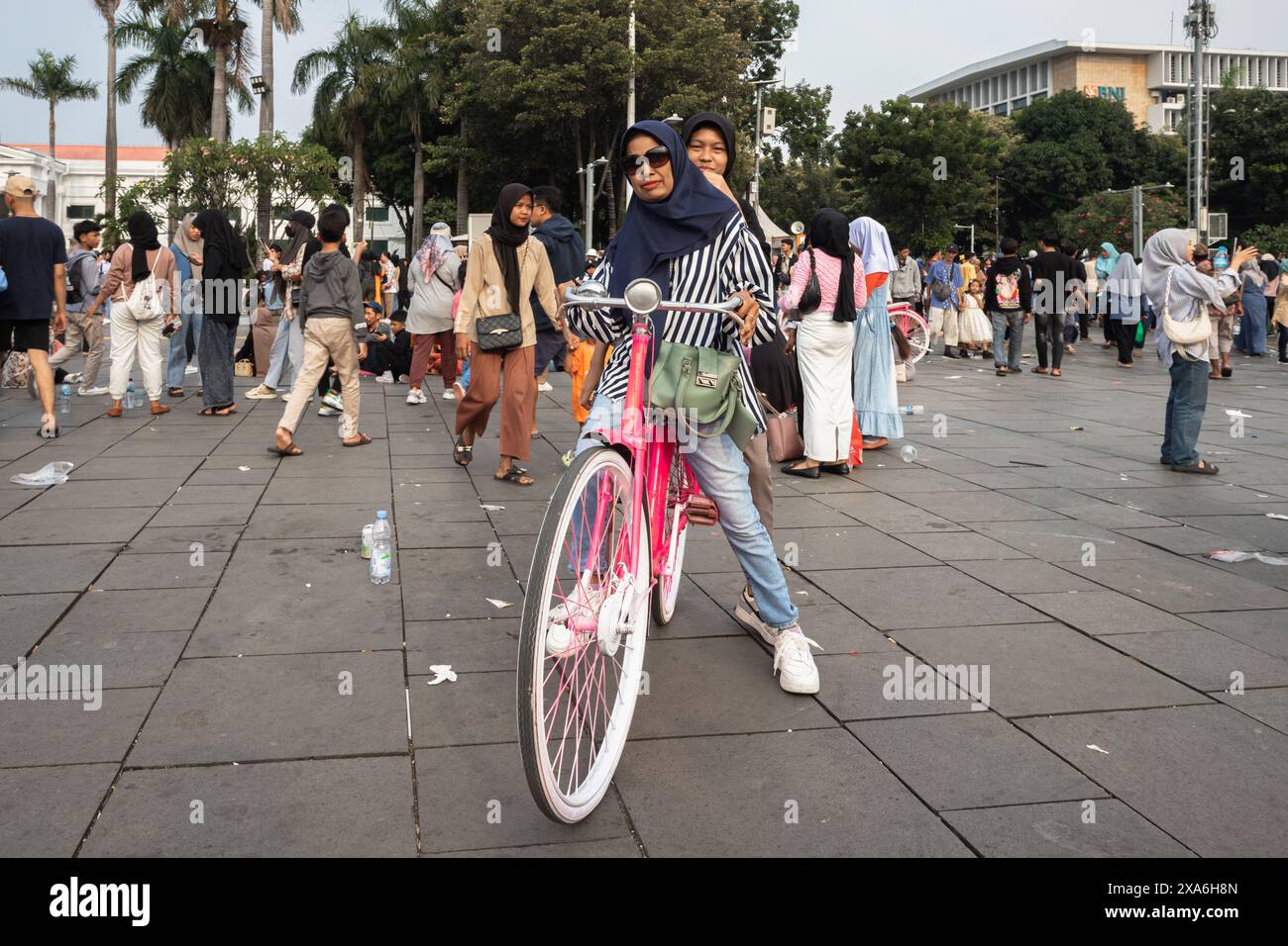 Un'affollata scena di strada di Giacarta con una donna in bicicletta Foto Stock