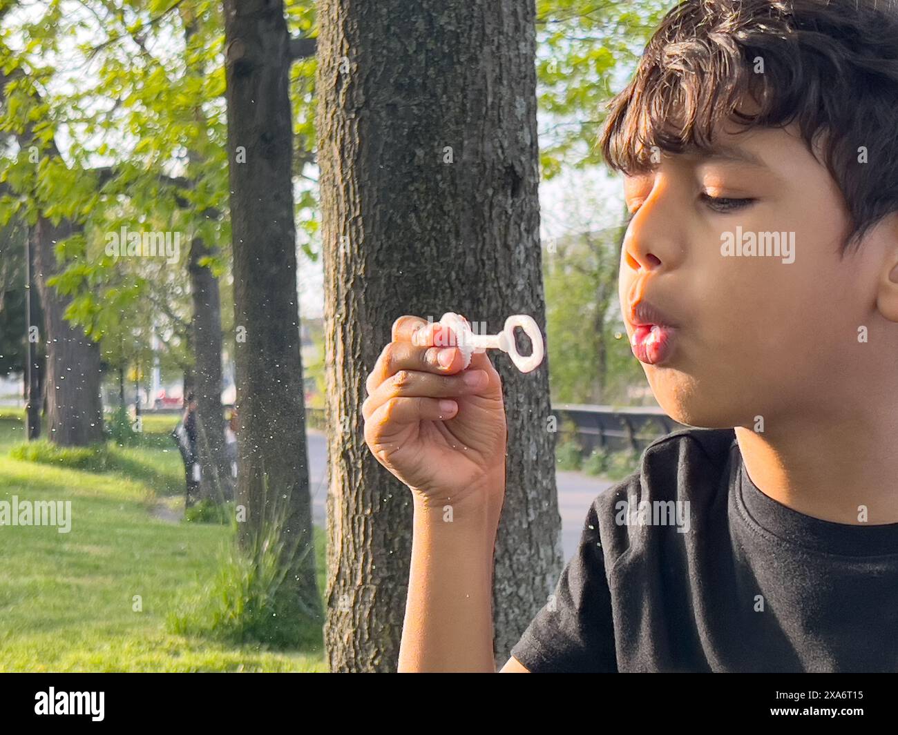 Un ragazzo che soffia una bolla con le dita sollevate Foto Stock