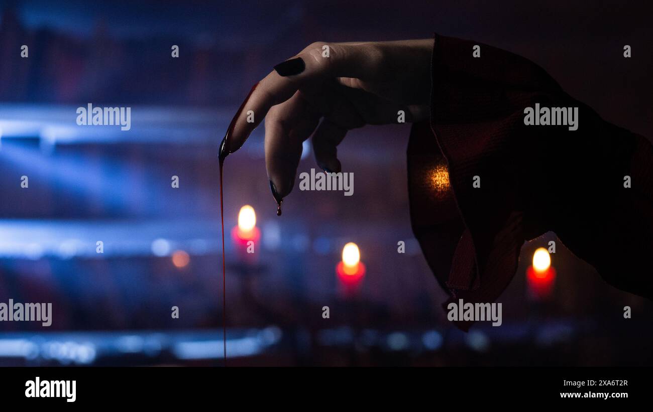 Le candele rosse bruciate con il sangue che cade dalle dita della mano Foto Stock