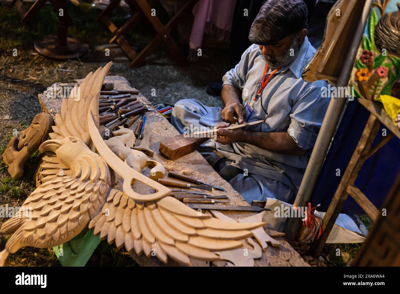 Un artigiano che scolpisce un'aquila di legno al festival Lok Mela in Pakistan Foto Stock