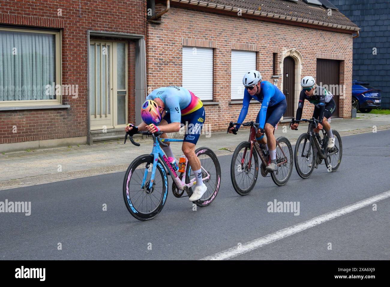 Tre uomini che pedalano lungo strade urbane in edifici alti Foto Stock