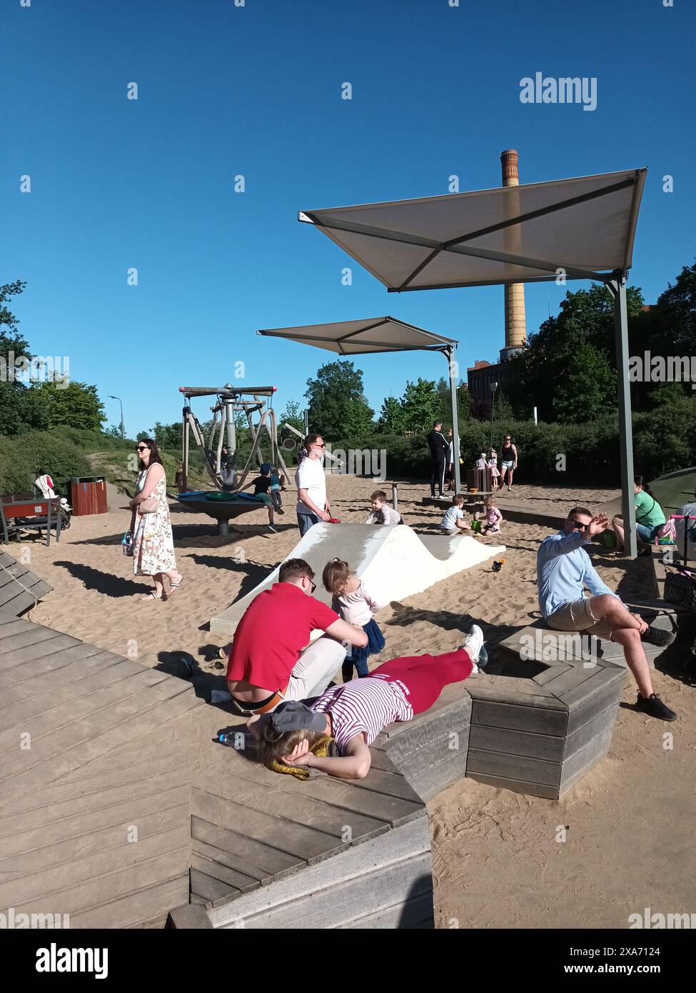 Un gruppo di persone che si godono una spiaggia sabbiosa con uno scivolo Foto Stock