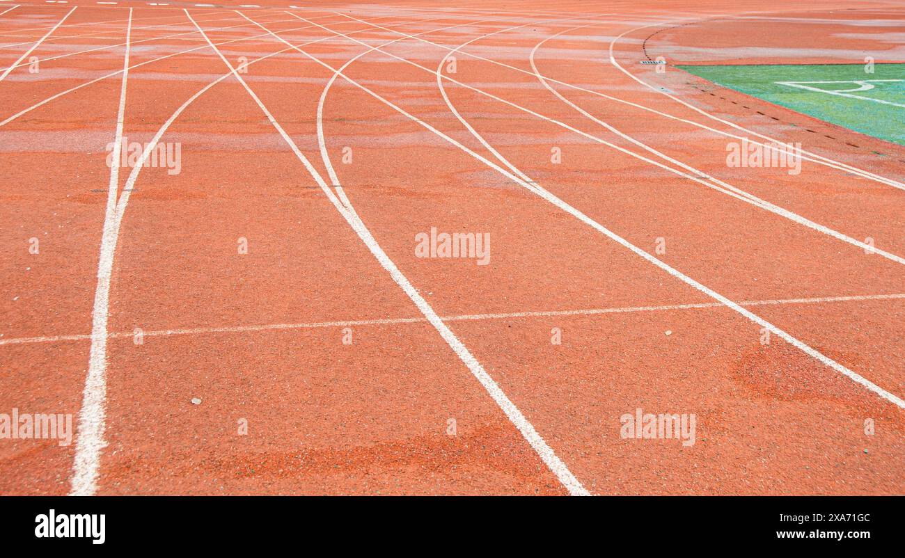 La pista rossa brillante di un'università di Wuhan. La curva bianca si interseca con la linea retta. Foto Stock