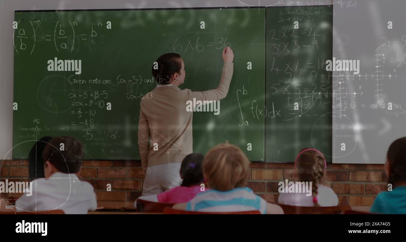 Immagine di una maestra caucasica che scrive su lavagna in classe piena di studenti Foto Stock