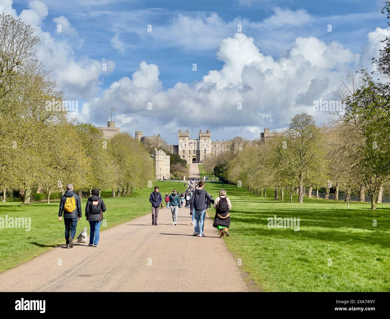 Un gruppo di individui che passeggiano su un sentiero verso un castello lontano Foto Stock