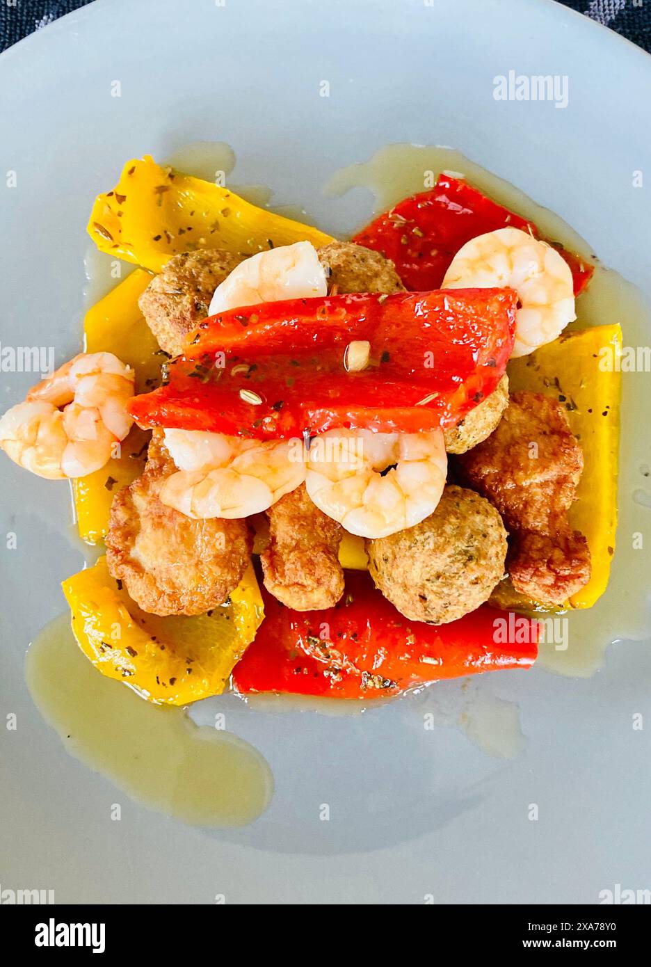 Un piatto di gamberetti, peperoni cotti e polpette su un piatto oleoso Foto Stock