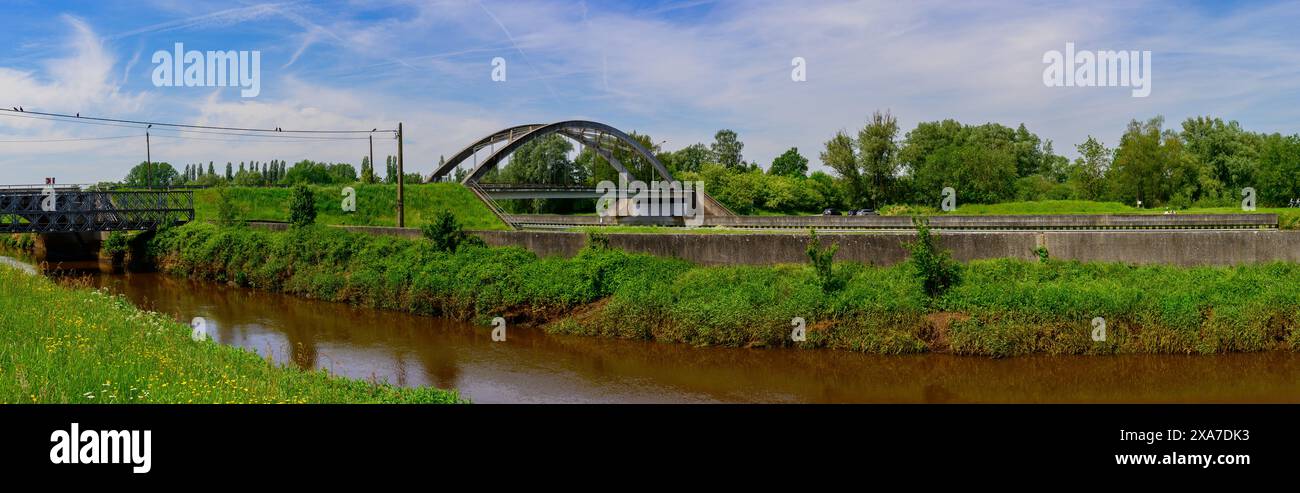 Una vista panoramica di un bellissimo paesaggio con molta vegetazione, un fiume con un ponte ad arco per i trasporti Foto Stock