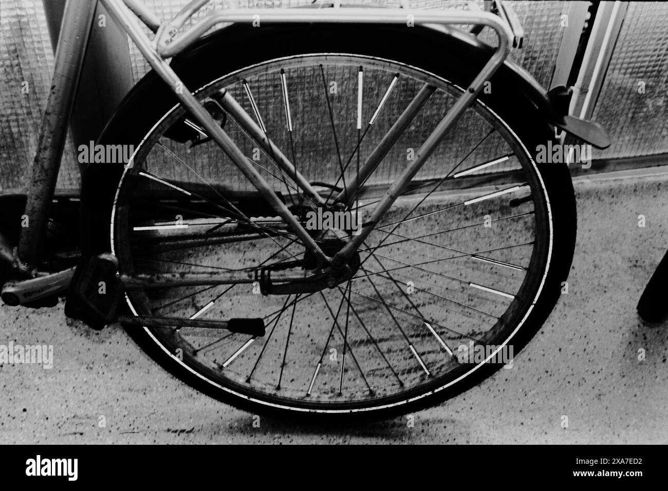 Immagine monocromatica di una bicicletta parcheggiata contro un muro Foto Stock