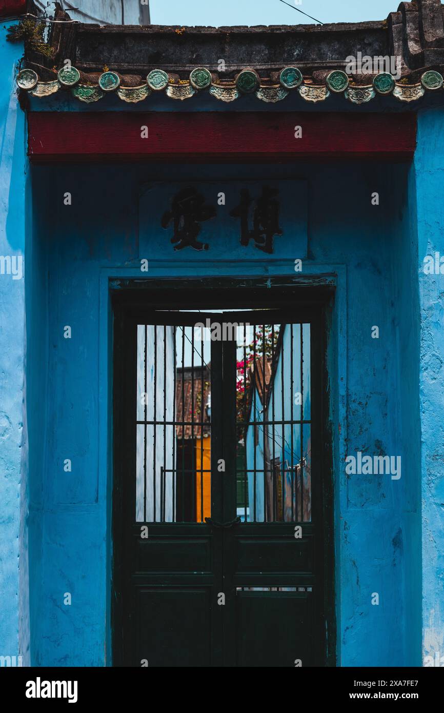 Un ingresso alla casa vintage blu con persiane rosse Foto Stock