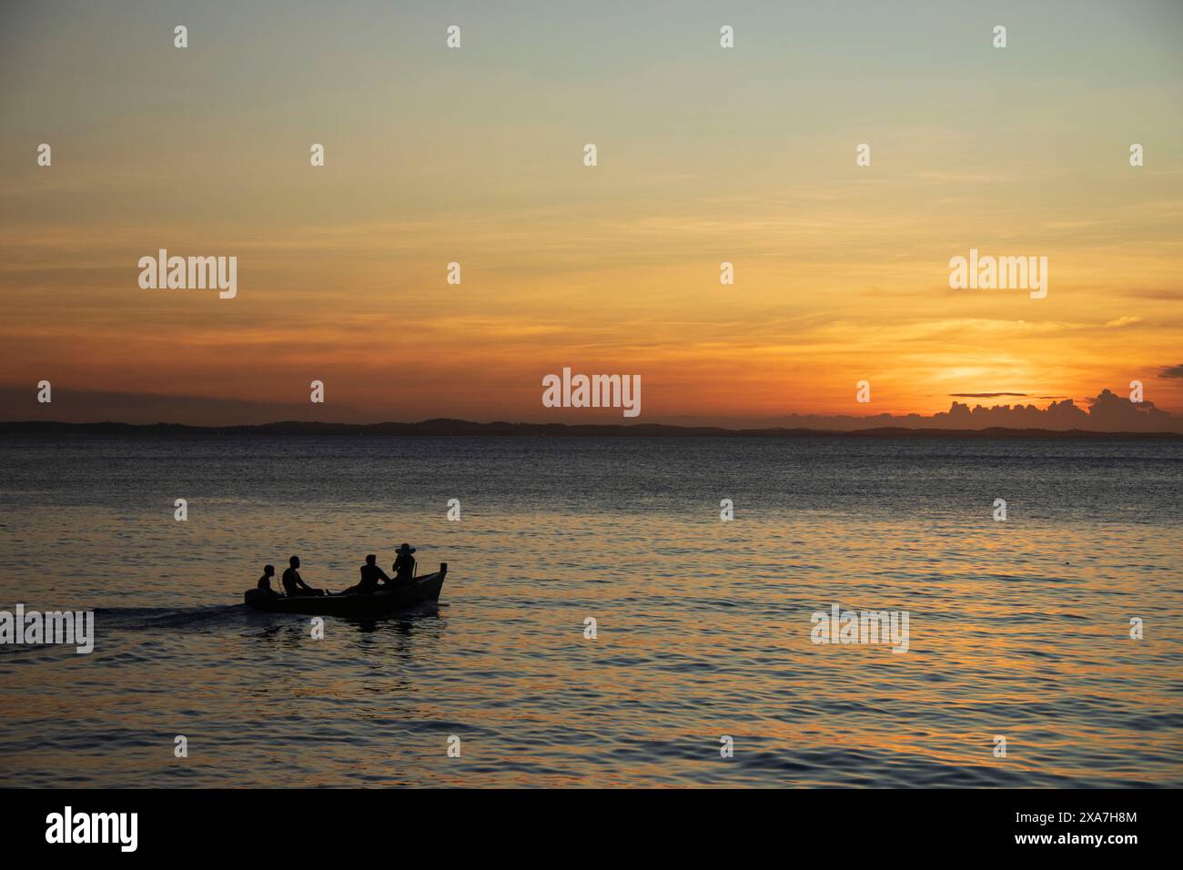 Gli individui in canoa sull'oceano durante il tramonto a Todos os Santos Bay Foto Stock