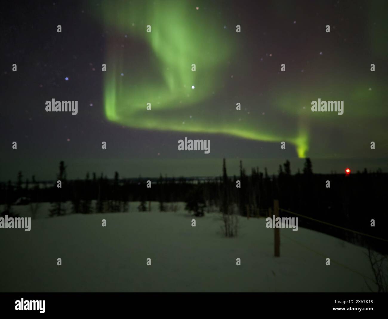 La vibrante aurora boreale illumina il cielo sopra una strada deserta in una notte serena Foto Stock