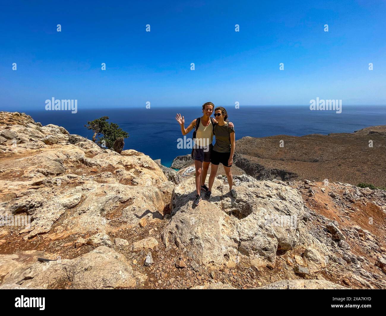 Un gruppo di individui che posano sulla scogliera che si affaccia sull'oceano in Grecia Foto Stock