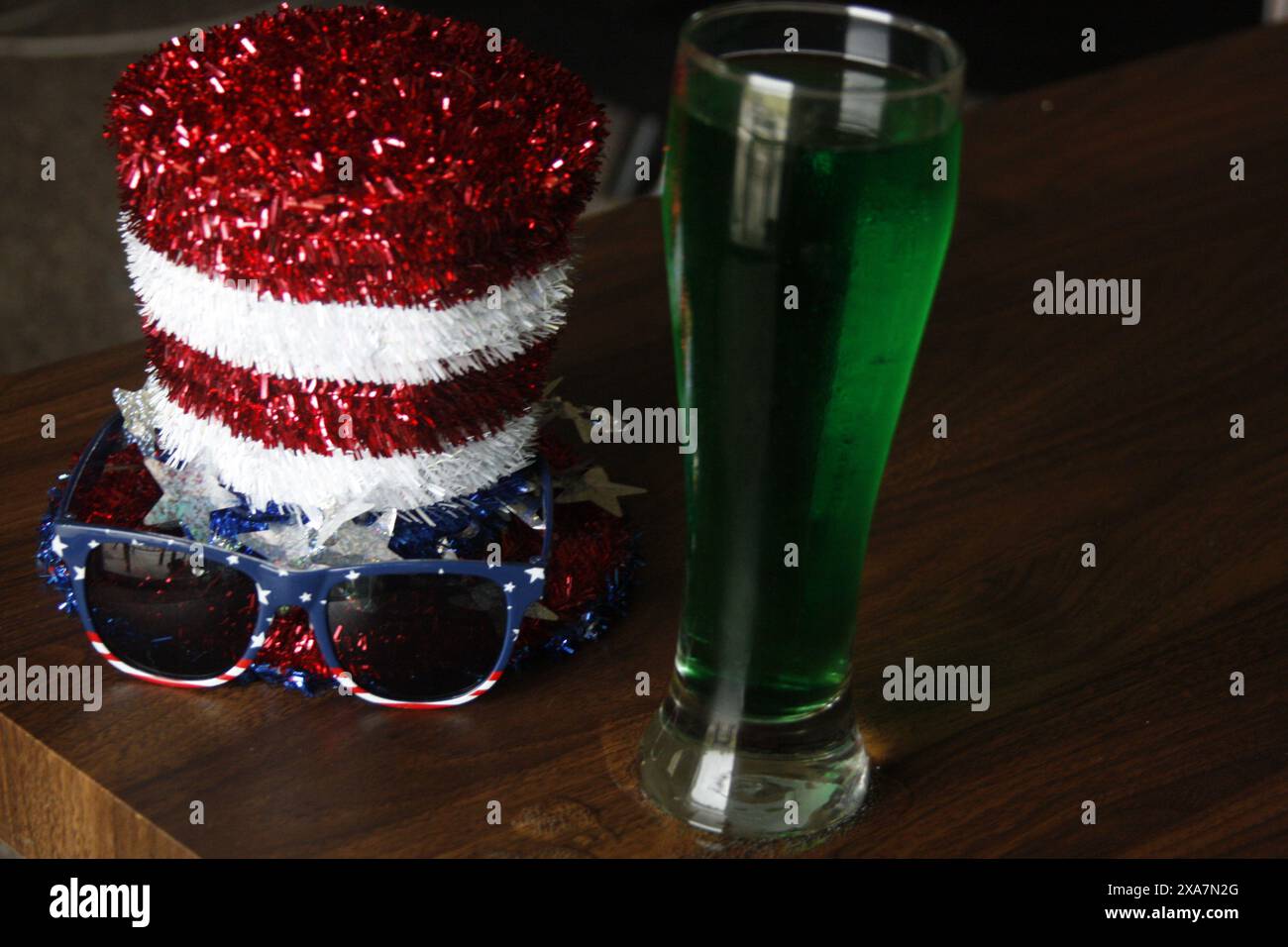 Un bicchiere, un cappello e occhiali da sole su un tavolo Foto Stock