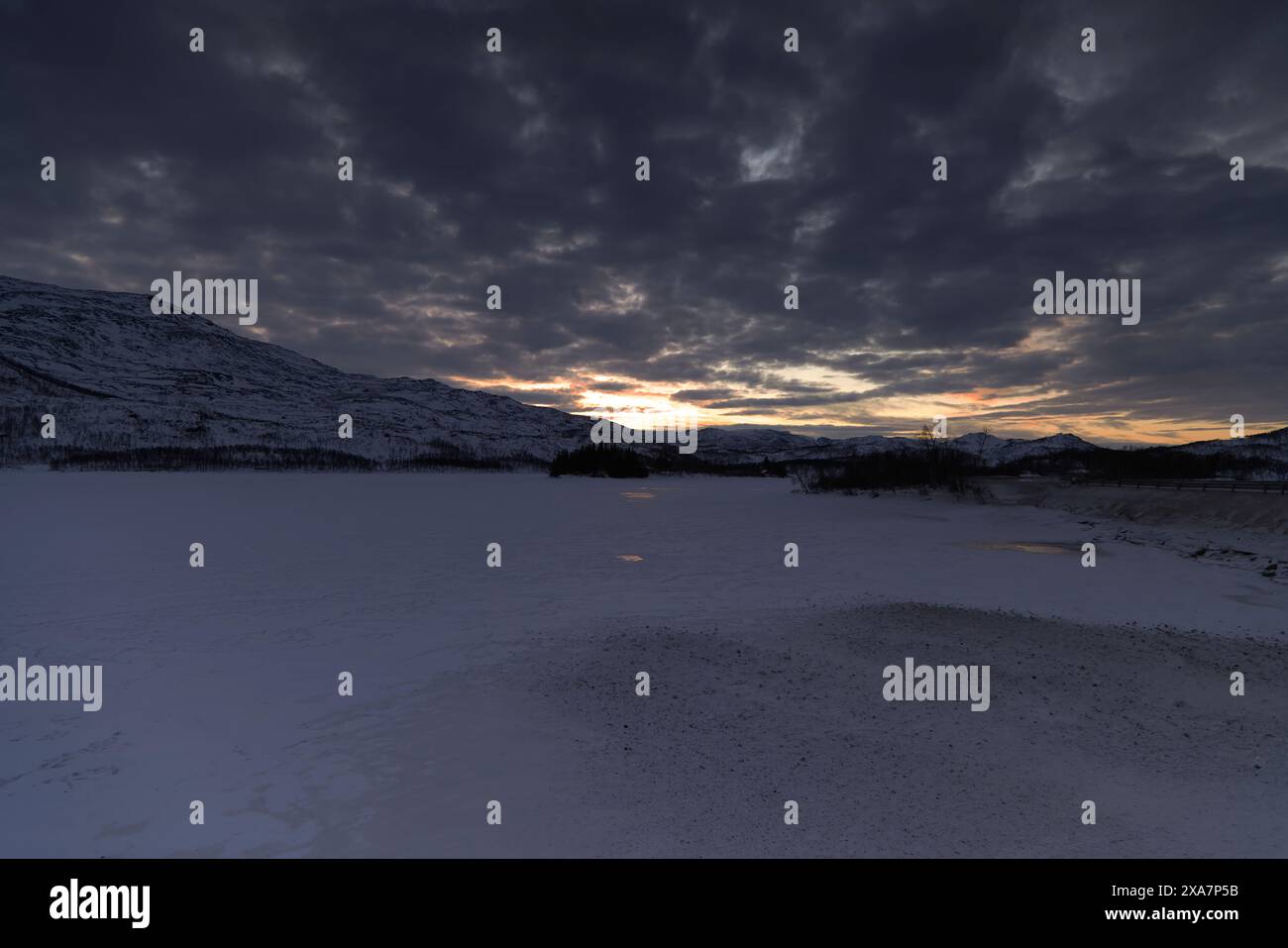 Il sole che tramonta sul campo innevato Foto Stock
