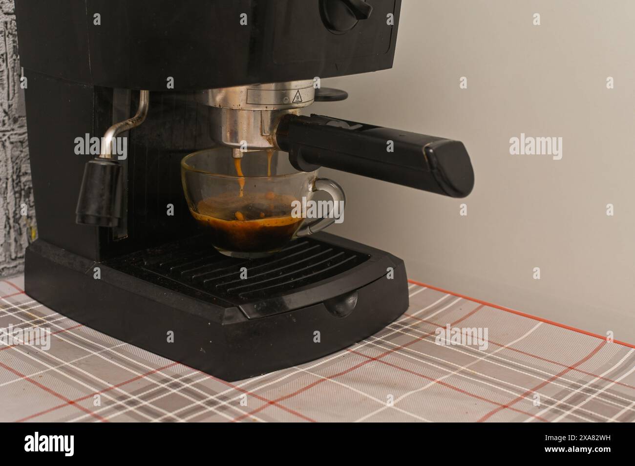 Una macchina per il caffè versa il caffè in una tazza di vetro in cucina Foto Stock