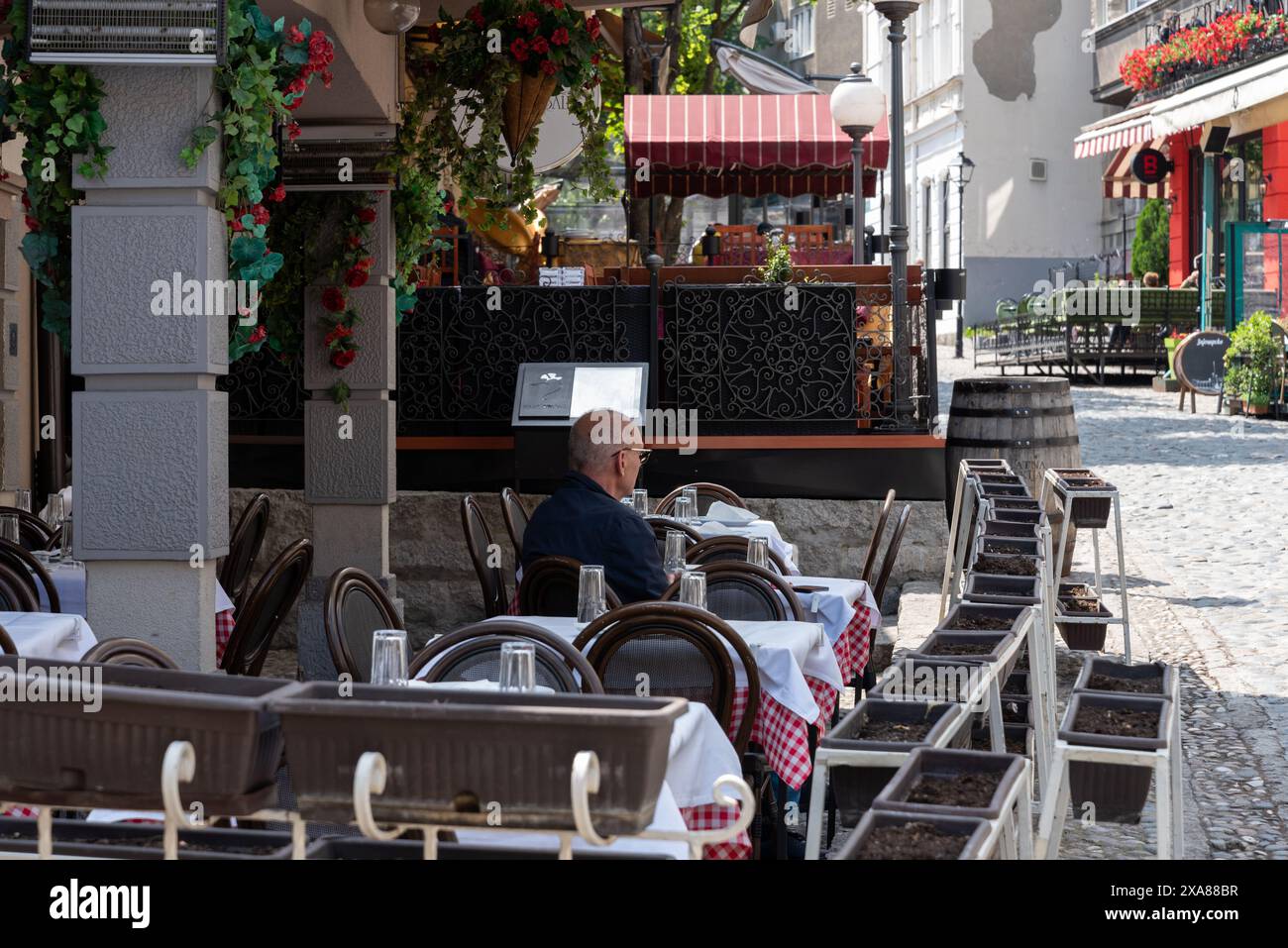Un anziano gentiluomo si gode il suo caffè mattutino da solo in uno dei caffè di Skardarlija a Belgrado. Aprile 2024. Foto Stock